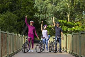 Team asiatischer Radsportfreunde, die sich im öffentlichen Park mit dem Fahrrad auf der Brücke ausruhen foto