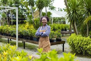 Porträt einer afroamerikanischen Gärtnerin, die in ihrem Baumschulgartenzentrum für Sommerhobby und Gartenbaukonzept arbeitet foto