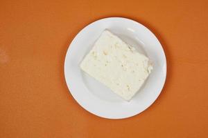 Feta-Käse auf einem Teller auf orangefarbenem Hintergrund foto