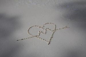 Herzen auf den Sand eines Strandes gezeichnet foto