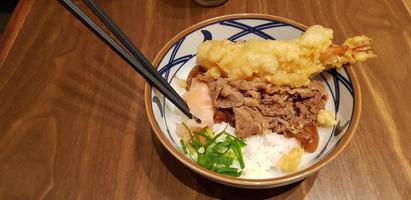 japanisches traditionelles essen rindfleisch teriyaki mit stickt-reis und tempura-garnelen geschnittenen frühlingszwiebeln in einer schüssel foto