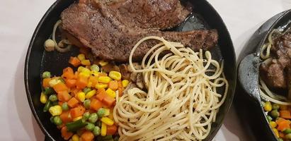 das beste Essen der Welt Rindersteak zusammen mit Bratkartoffeln mit köstlicher Pilzsauce und Salat auf einem schönen Teller mit schwarzen Streifen foto