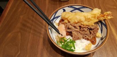 japanisches traditionelles essen rindfleisch teriyaki mit stickt-reis und tempura-garnelen geschnittenen frühlingszwiebeln in einer schüssel foto