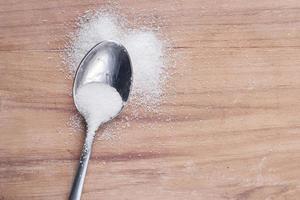 weißer Zucker auf Löffel auf Holztisch foto
