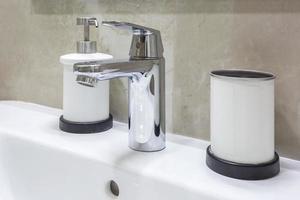 Seifen- und Shampoo-Spender in der Nähe von Keramik-Waschbecken mit Wasserhahn im teuren Loft-Badezimmer foto