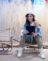 porträt schöne junge mädchen frau asiatisch hübsch lächeln eine person allein sitzt auf stuhl camping mit tablet verband das internet mit der arbeit. reise reise vorzelt freiheit entspannen glücklich genießen