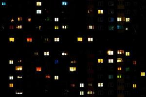 Flaches Nachtpanorama mit mehrfarbigem Licht in Fenstern von mehrstöckigen Gebäuden. Leben in der Großstadt foto