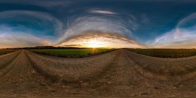 Vollständiges, nahtloses sphärisches Hdri-Panorama 360-Grad-Winkelansicht auf Schotterstraße zwischen Feldern im Sommerabendsonnenuntergang mit fantastischen Wolken in equirectangularer Projektion, bereit für vr ar virtuelle Realität foto