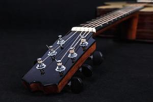 Stimmwirbel auf hölzernem Maschinenkopf von sechs Saiten Akustikgitarrenhals auf schwarzem Hintergrund foto