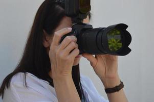 Mädchen mit einer Kamera auf weißem Hintergrund. das mädchen fotografiert mit einer professionellen kamera. foto