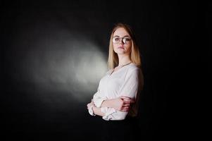 Studioporträt einer blonden Geschäftsfrau mit Brille, weißer Bluse und schwarzem Rock vor dunklem Hintergrund. erfolgreiche frau und stilvolles mädchenkonzept. foto