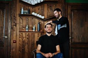 hübscher bärtiger mann im friseursalon, friseur bei der arbeit. Kopf waschen. foto