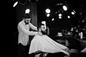 hübscher bärtiger mann im friseursalon, friseur bei der arbeit. foto