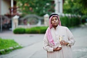 arabischer geschäftsmann aus dem nahen osten posierte auf der straße mit einer goldenen tasse an den händen. foto