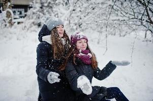 Zwei lustige Freundinnen, die sich am verschneiten Wintertag in der Nähe von schneebedeckten Bäumen amüsieren. foto