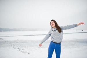 lustige mädchen tragen auf kapuzenpullover und jeans, am zugefrorenen see im wintertag. foto