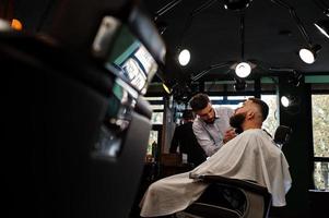 hübscher bärtiger mann im friseursalon, friseur bei der arbeit. foto