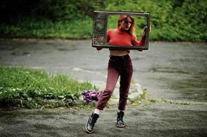Modeporträt des rothaarigen sexy Mädchens im Freien. Modell attraktive dramatische Frau mit alter TV-Box. foto