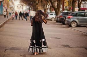 hübsches indisches mädchen im schwarzen saree-kleid posierte im freien auf der herbststraße. foto