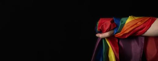 lgbtq-stolzflagge auf schwarzem hintergrund. lgbt-regenbogenfahne in schwuler hand. foto