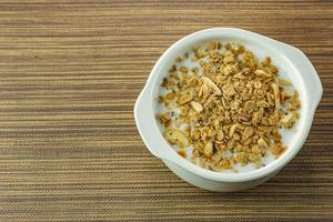 Morgenfutter Mandelflocken und Milch in weißer Schüssel auf Holztisch. foto