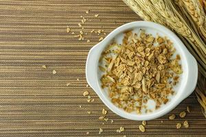 Morgenfutter Mandelflocken und Milch in weißer Schüssel auf Holztisch. foto