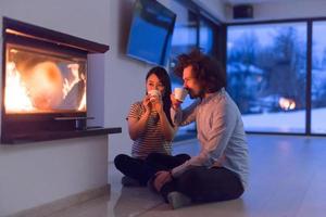 glückliches multiethnisches Paar, das vor dem Kamin sitzt foto