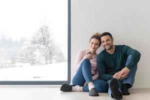 junges paar sitzt zu hause auf dem boden neben dem fenster foto