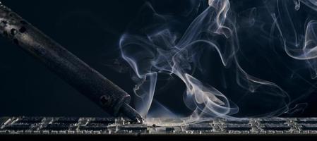 Hintergrund des rauchenden Lötkolbens auf dunklem Hintergrund. foto