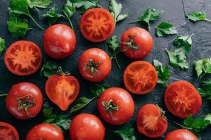 frisches Gemüse auf dunklem Hintergrund. reife rote Tomaten und grüne Petersilie aus dem Garten geerntet. Wassertropfen auf Bio-Produkten. leckere vegane Produkte foto