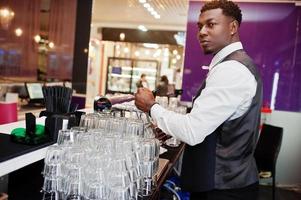 Afroamerikanischer Barkeeper an der Bar, der im Pub frisches Bier vom Fass in das Glas gießt. foto