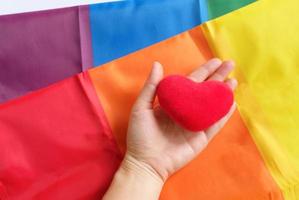 die regenbogenflagge ist ein symbol des stolzes lgbt und lgbtq mit der hand, die herzform hält, liebe gewinnt konzept foto