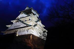 Schloss Osaka in Osaka, Japan, beleuchtet von Scheinwerfern in der Abenddämmerung. foto