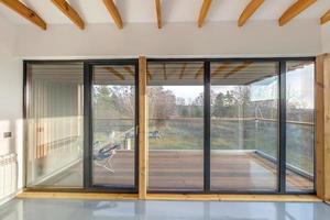 Weiße, leere Wohnung mit Panoramafenstern und Holzsparrendecke im Ferienhaus, mit Blick auf die Natur im Wald foto