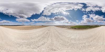 Vollständiges, nahtloses sphärisches HDR-Panorama 360-Grad-Winkelansicht auf weißer Sandkiesstraße zwischen Feldern am Frühlingstag mit fantastischen Wolken in gleichrechteckiger Projektion, bereit für vr-Virtual-Reality-Inhalte foto