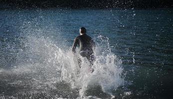 Triathlonsportler beginnt mit dem Schwimmtraining auf dem See foto