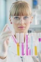 Forscherin hält ein Reagenzglas im Labor hoch foto