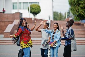 Gruppe von fünf afrikanischen College-Studenten, die gemeinsam Zeit auf dem Campus des Universitätshofs verbringen. Schwarze Afro-Freunde studieren und geben sich High Five.