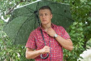 Mann mit Regenschirm im Regen foto