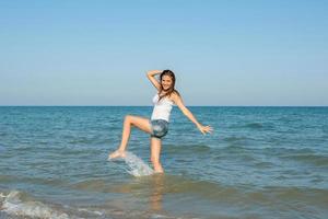 junges Mädchen, das das Wasser im Meer spritzt foto