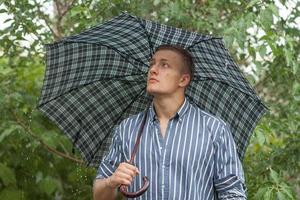 Mann mit Regenschirm im Regen foto