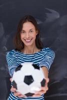 Frau hält einen Fußball vor Kreidezeichenbrett foto