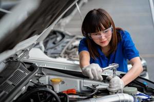 eine Kfz-Mechanikerin, die den Motor eines Autos überprüft. Ein Mechaniker inspiziert und wartet den Motor eines Autos oder Fahrzeugs. eine Kfz-Mechanikerin, die den Motor eines Autos überprüft. Automechaniker-Konzept foto