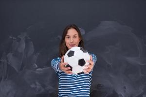 Frau hält einen Fußball vor Kreidezeichenbrett foto