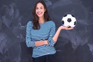 Frau hält einen Fußball vor Kreidezeichenbrett foto