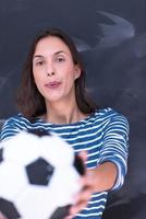 Frau hält einen Fußball vor Kreidezeichenbrett foto