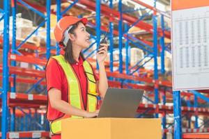 lagerarbeiter, der in der fabriklagerindustrie arbeitet und funkkommunikation nutzt, vorarbeiter in hardhat-sicherheitsweste mit funkgerät, das im logistikzentrum arbeitet foto