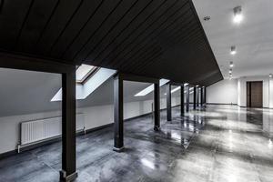 Leeres, unmöbliertes Loft-Mansardenzimmer mit Holzsäulen und nassem Betonboden auf Dachebene in schwarzer und Whote-Stilfarbe foto