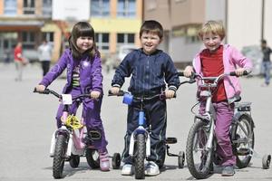 glückliche kindergruppe, die lernt, fahrrad zu fahren foto