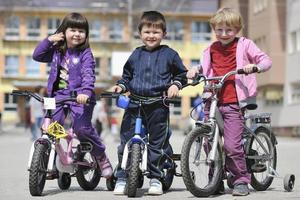 glückliche kindergruppe, die lernt, fahrrad zu fahren foto